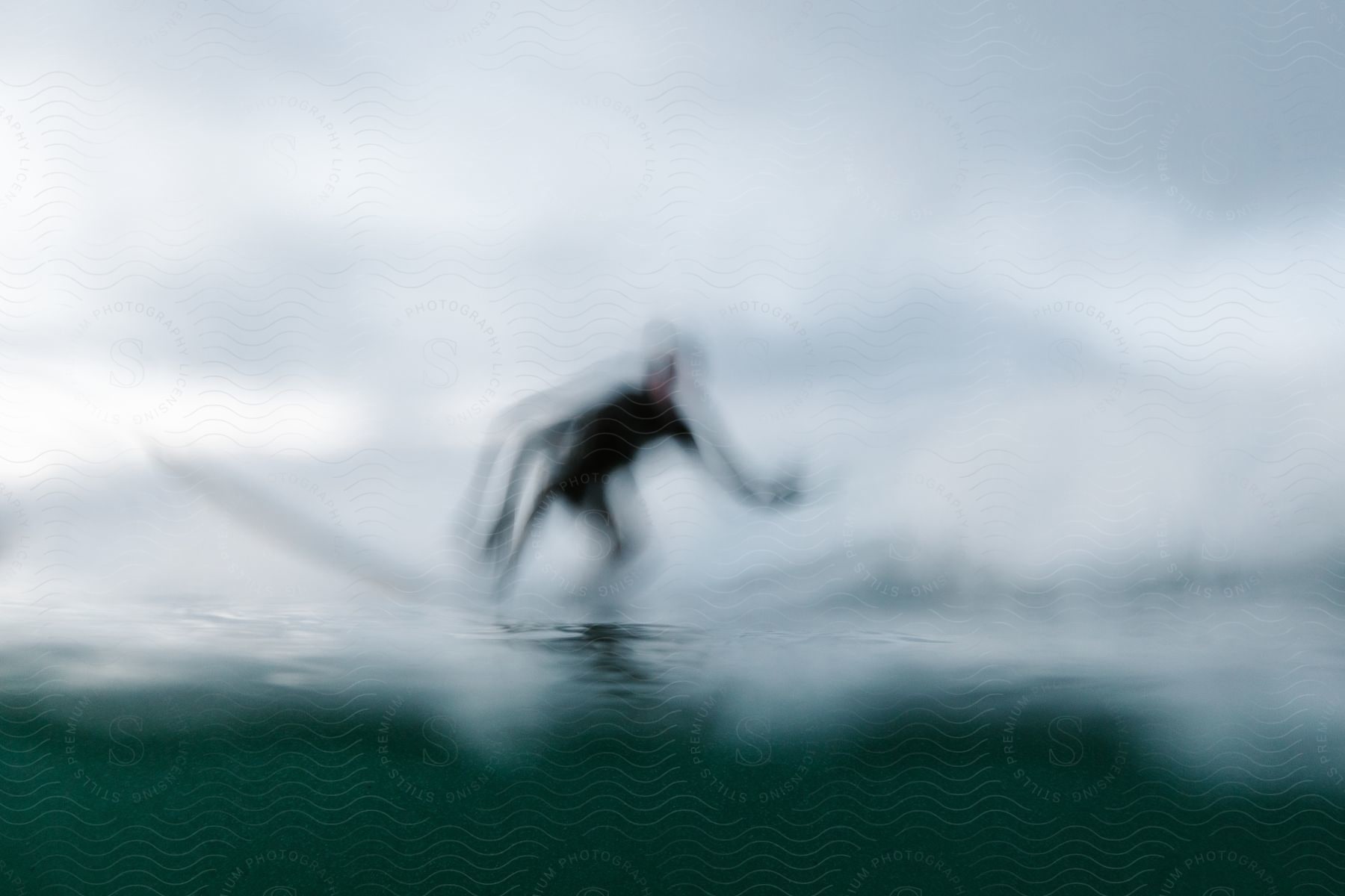 A person surfs in the ocean on a cloudy day