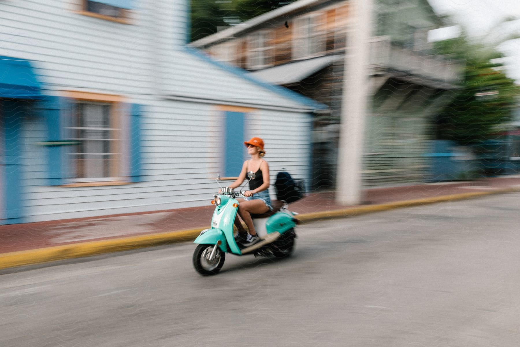 Woman rides moped along street in small town.