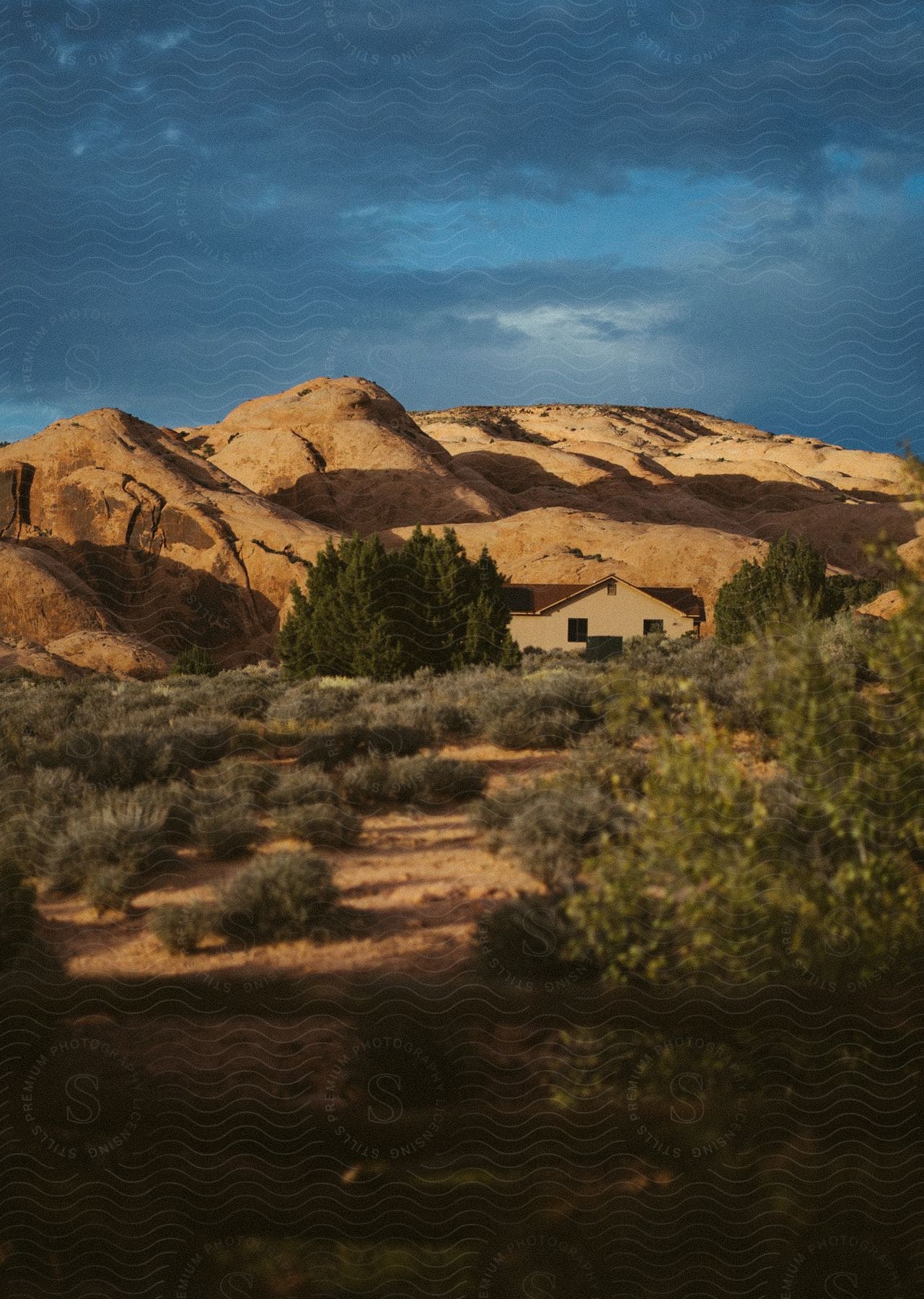 A house is seen in the desert with hills in the background