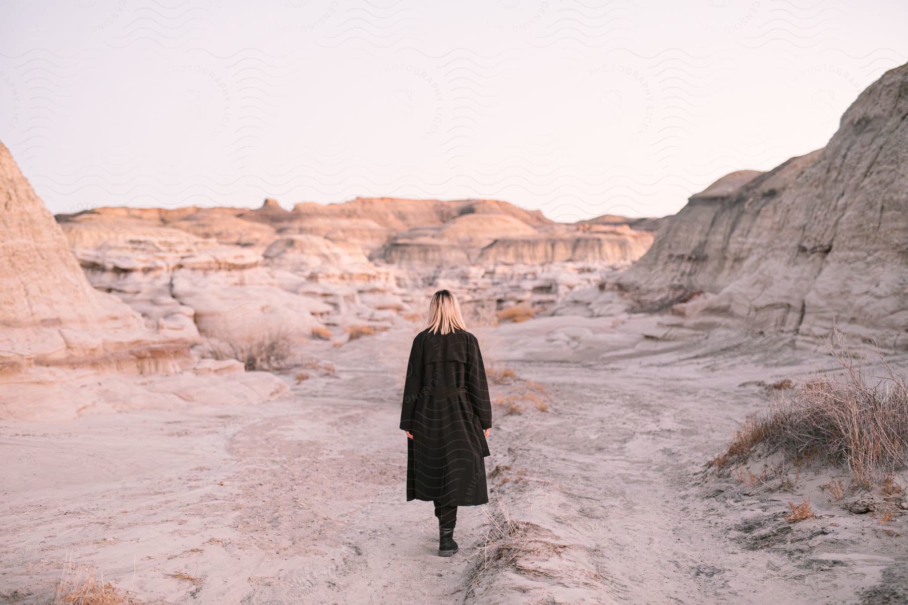 A woman stands in the mountains wearing a coat