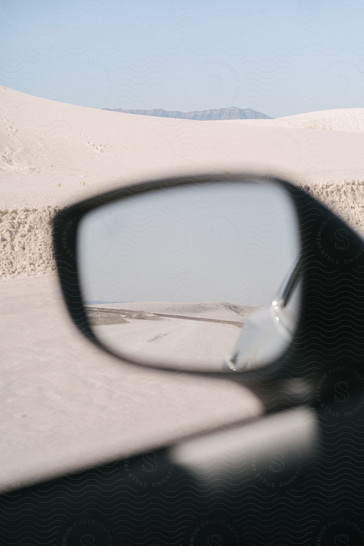 A desert scene seen through a car window with the side mirror in focus