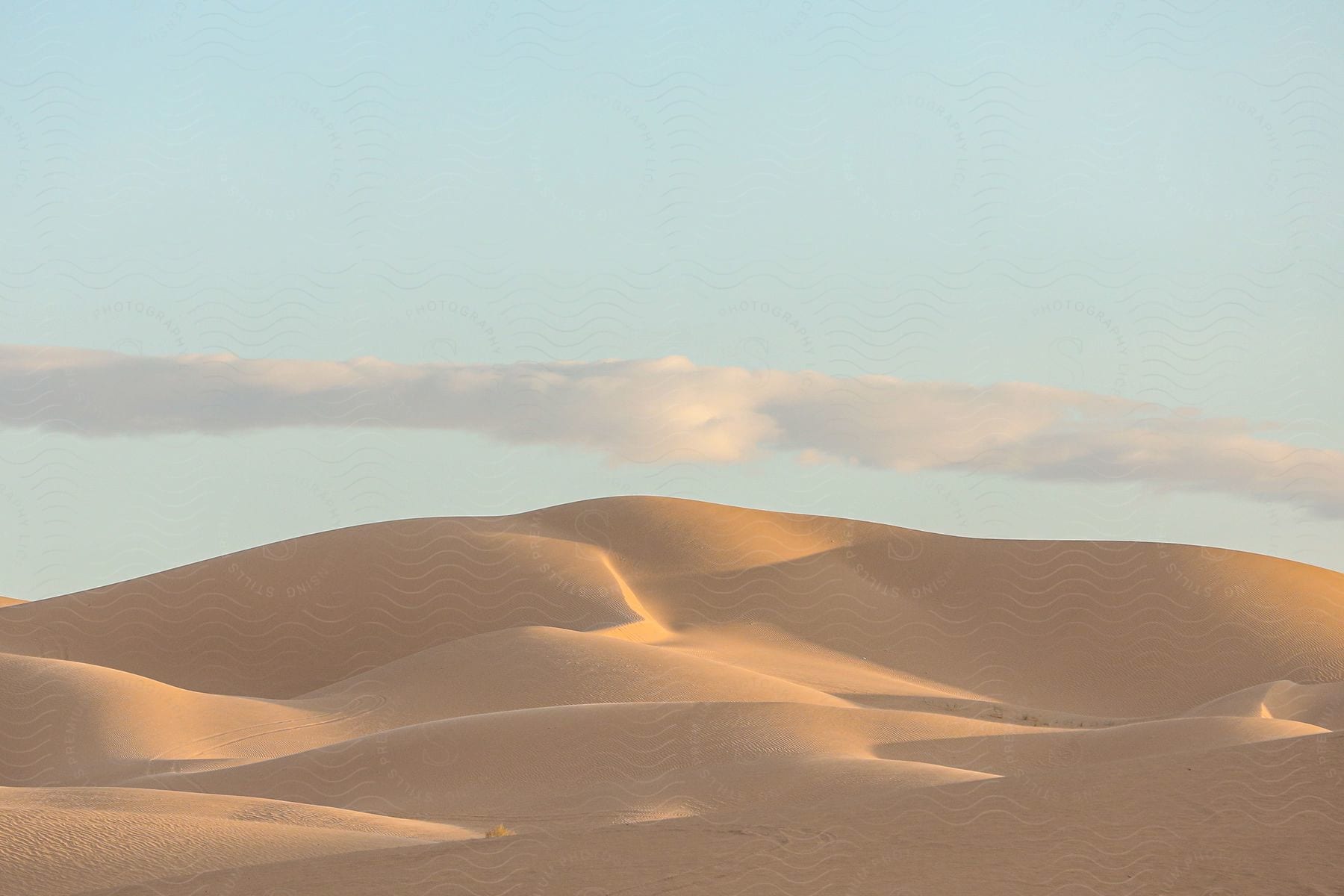 A barren desert landscape with sandy dunes and a cloudy sky