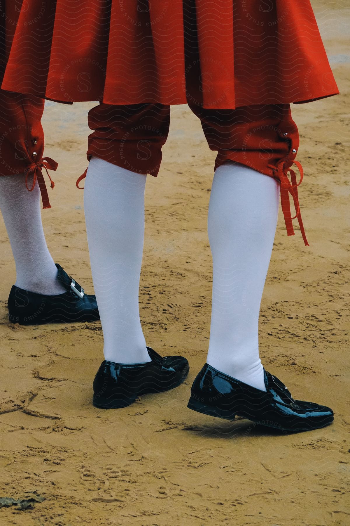 Stock photo of close up of the legs of a bullfight participant in a red ceremonial dress at daytime