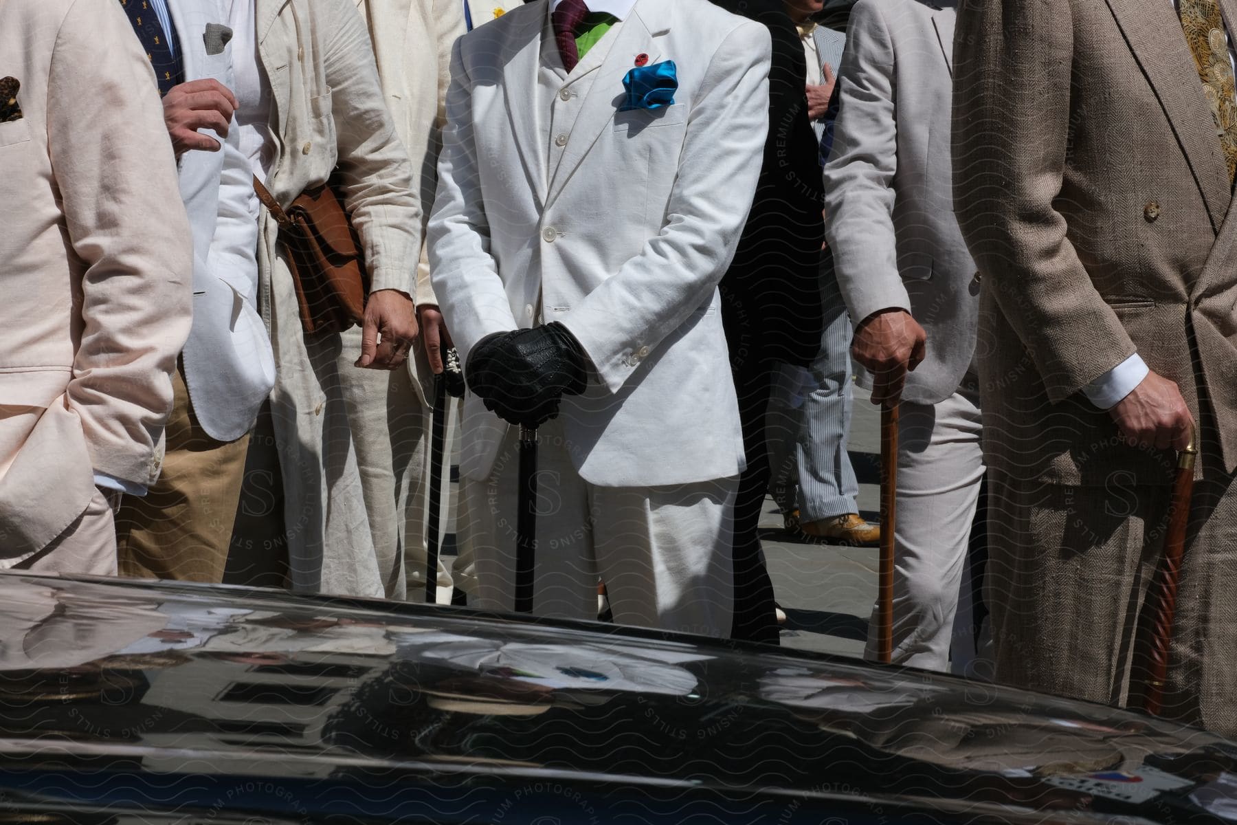 Welldressed men in suits standing confidently outside with a sleek car parked in front of them