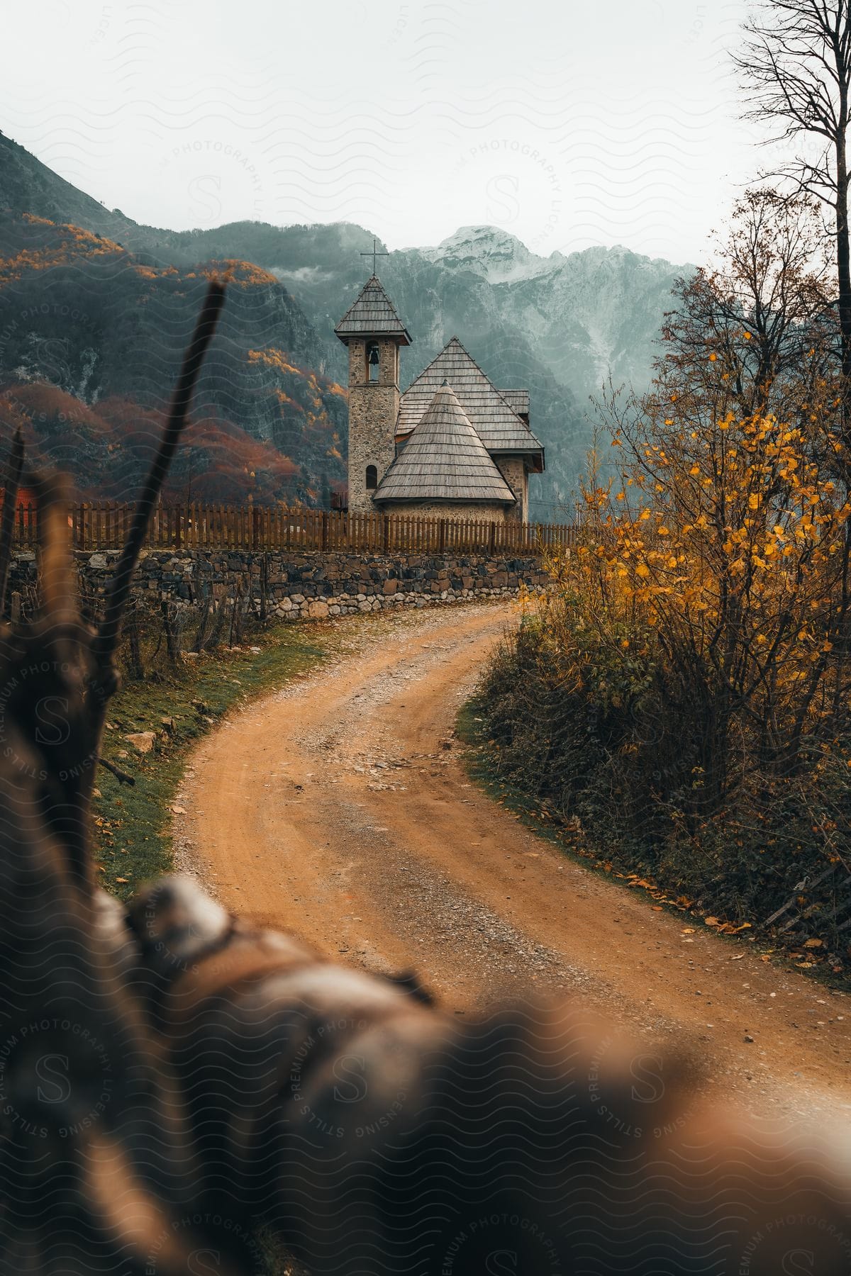 A dirt road leads to a small church in the countryside below mountains