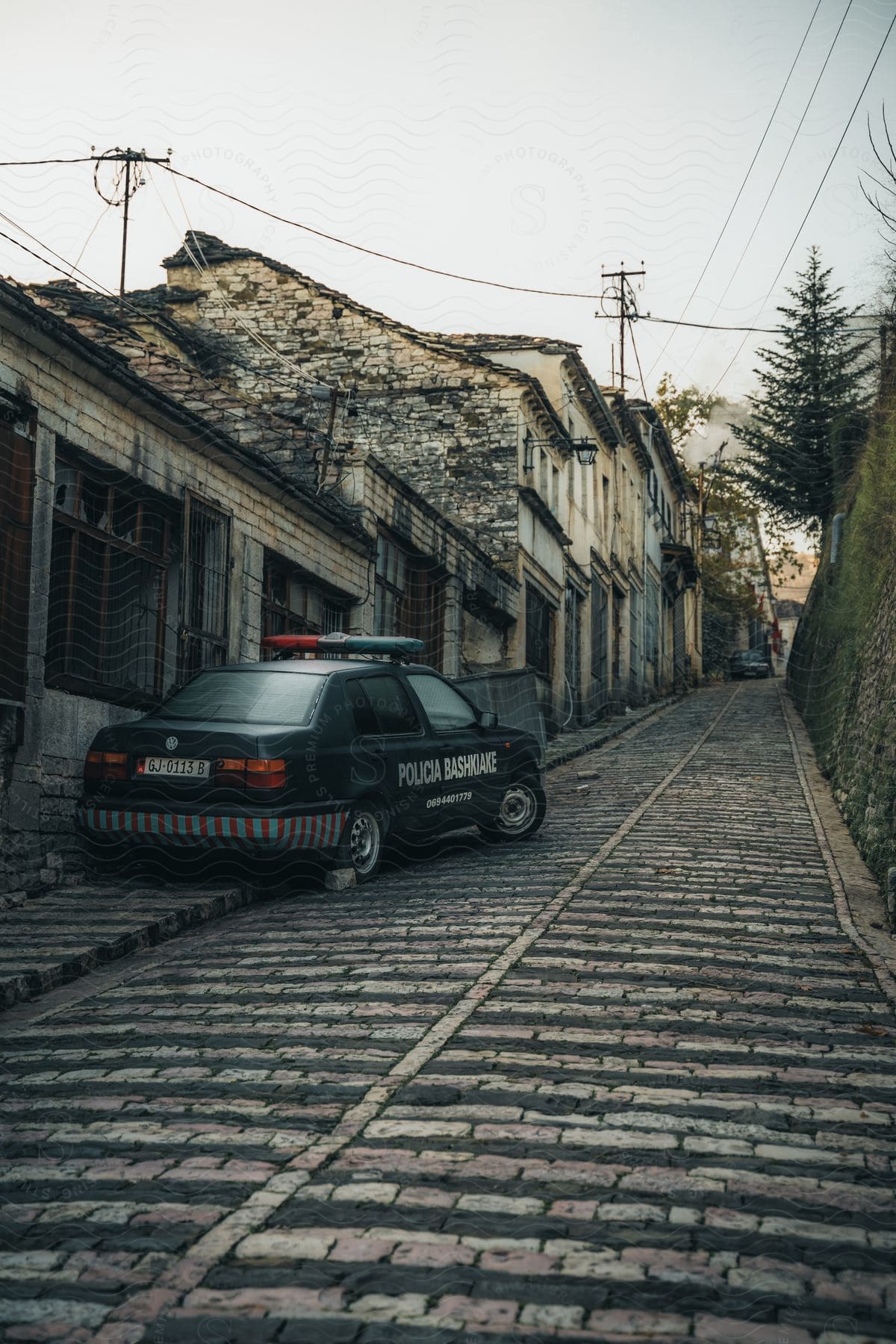 A police car parked on the sidewalk and brick road outside townhouses