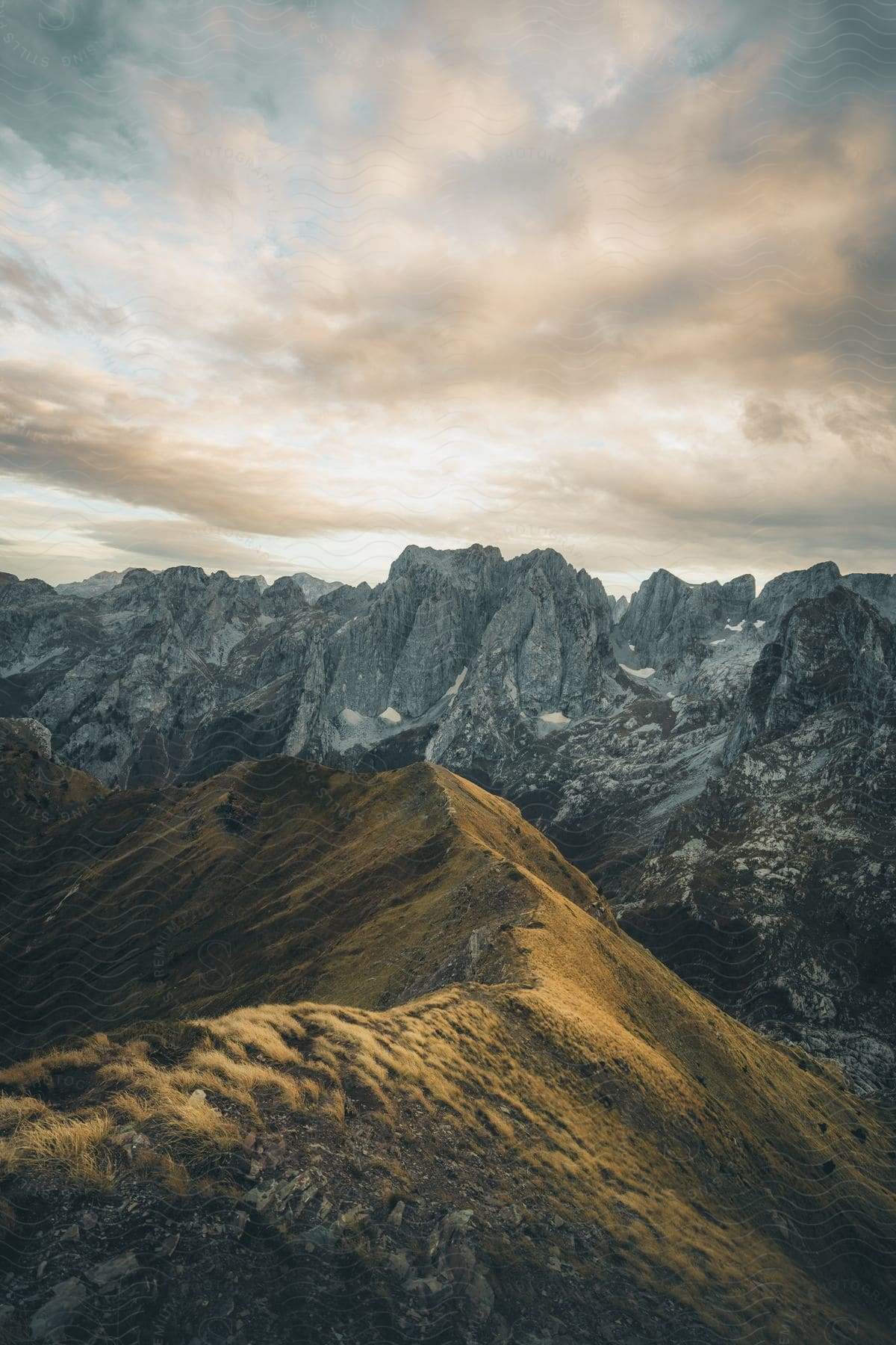 Mountain range with rocky and grassy terrain on a cloudy day