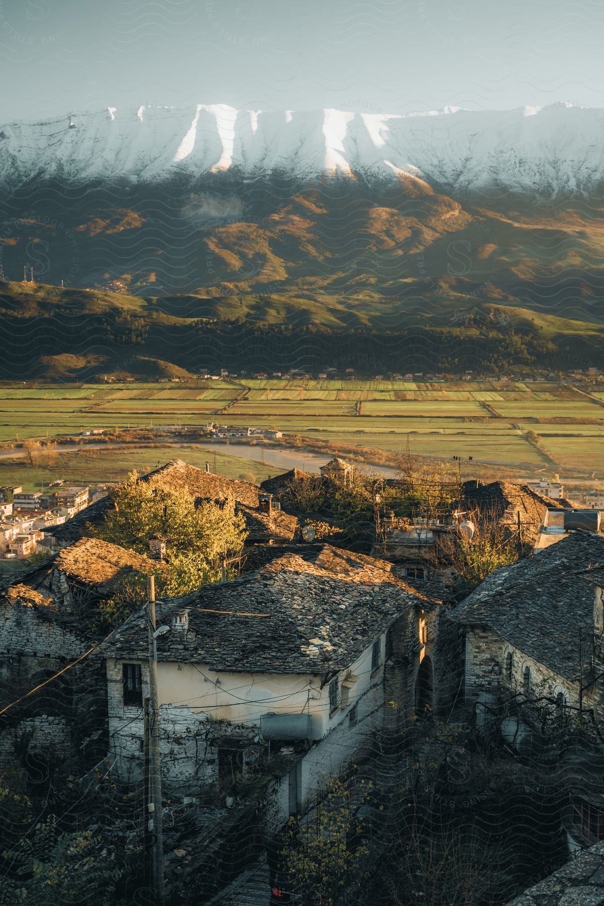 Dilapidated Farm Houses Near Farming Fields Hillsides And A Snowcovered Mountain