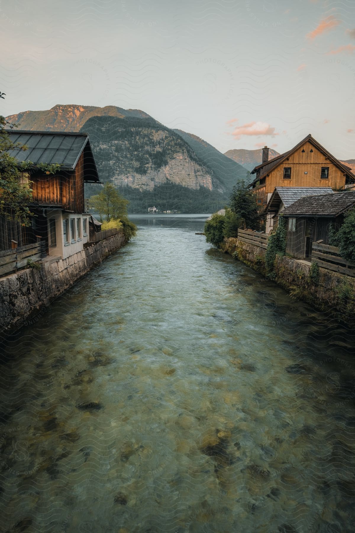 A stream of water flowing through a small town filling to larger body of water near the mountains