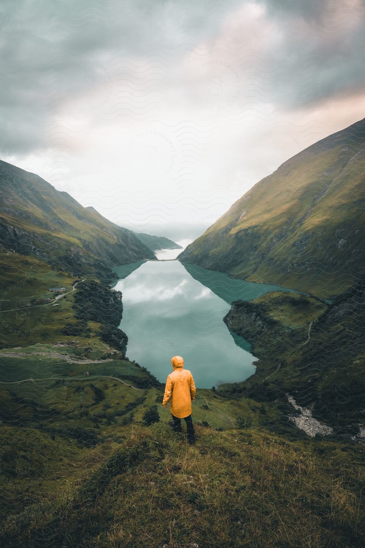 A hiker stands next to a river in the bottom of a canyon