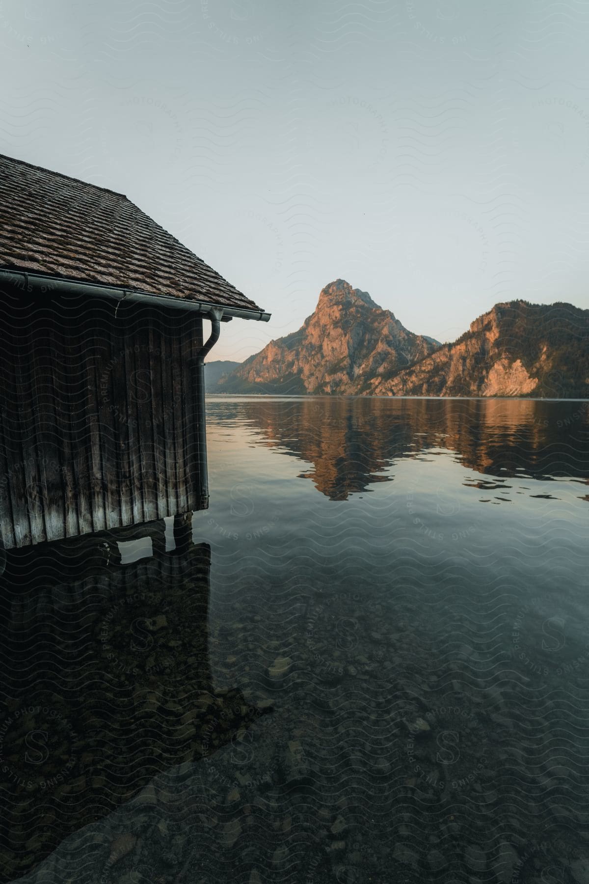 A landscape of mountains and a waterfront with a small shelter