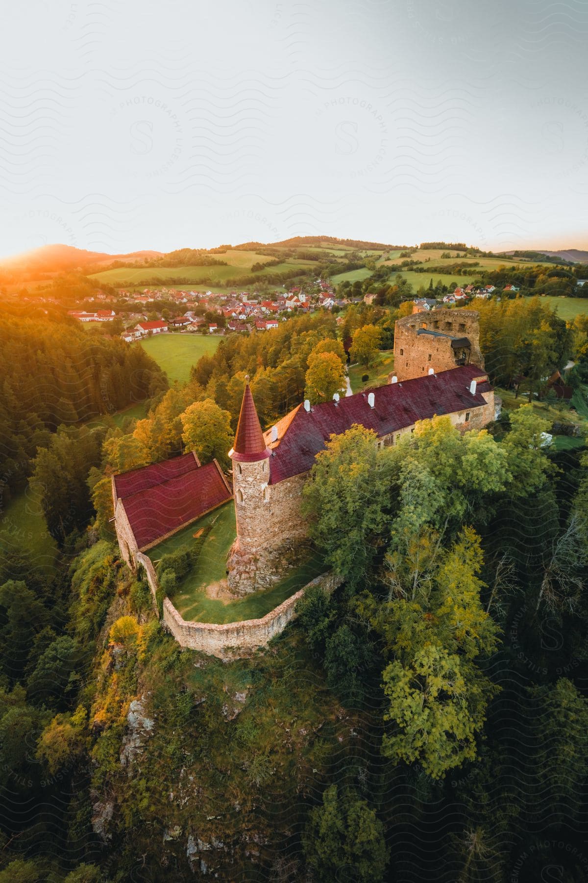 A village surrounded by grassy fields near an ancient fortress