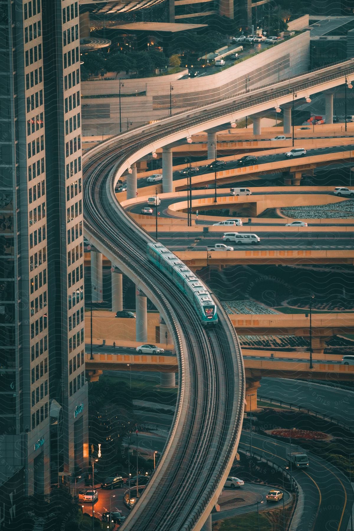 Busy city streets with cars a tall building on the left and a transportation train riding above the roads