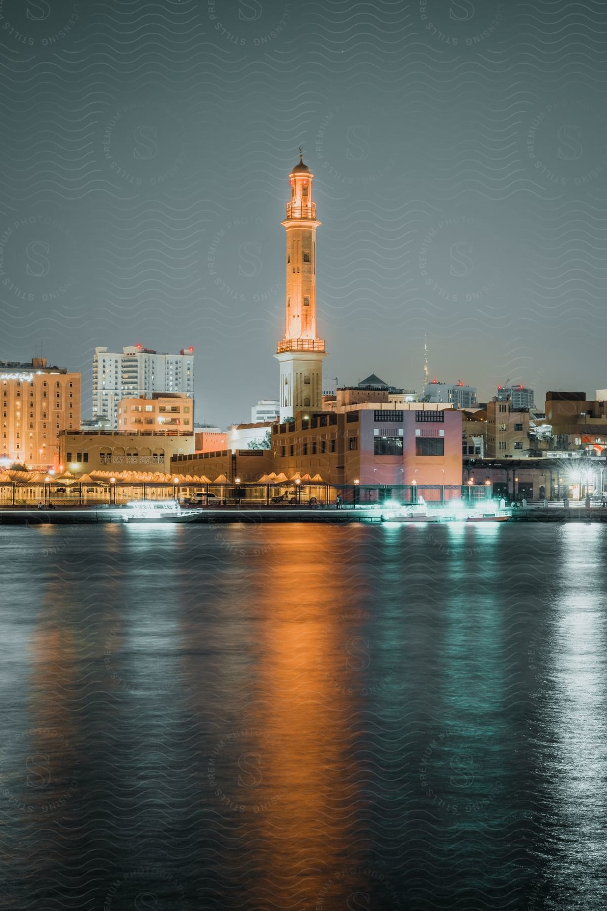 A city near a body of water at night with boats near the road