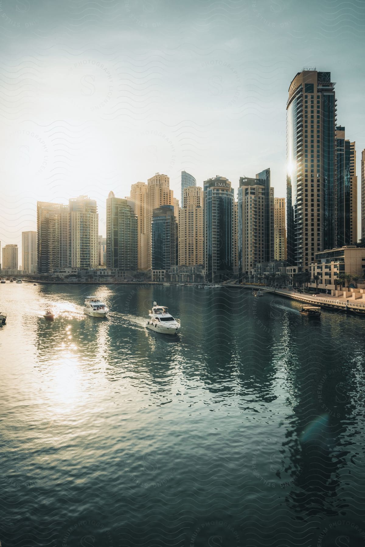 A city with tall buildings overlooks a waterway filled with boats on a sunny day