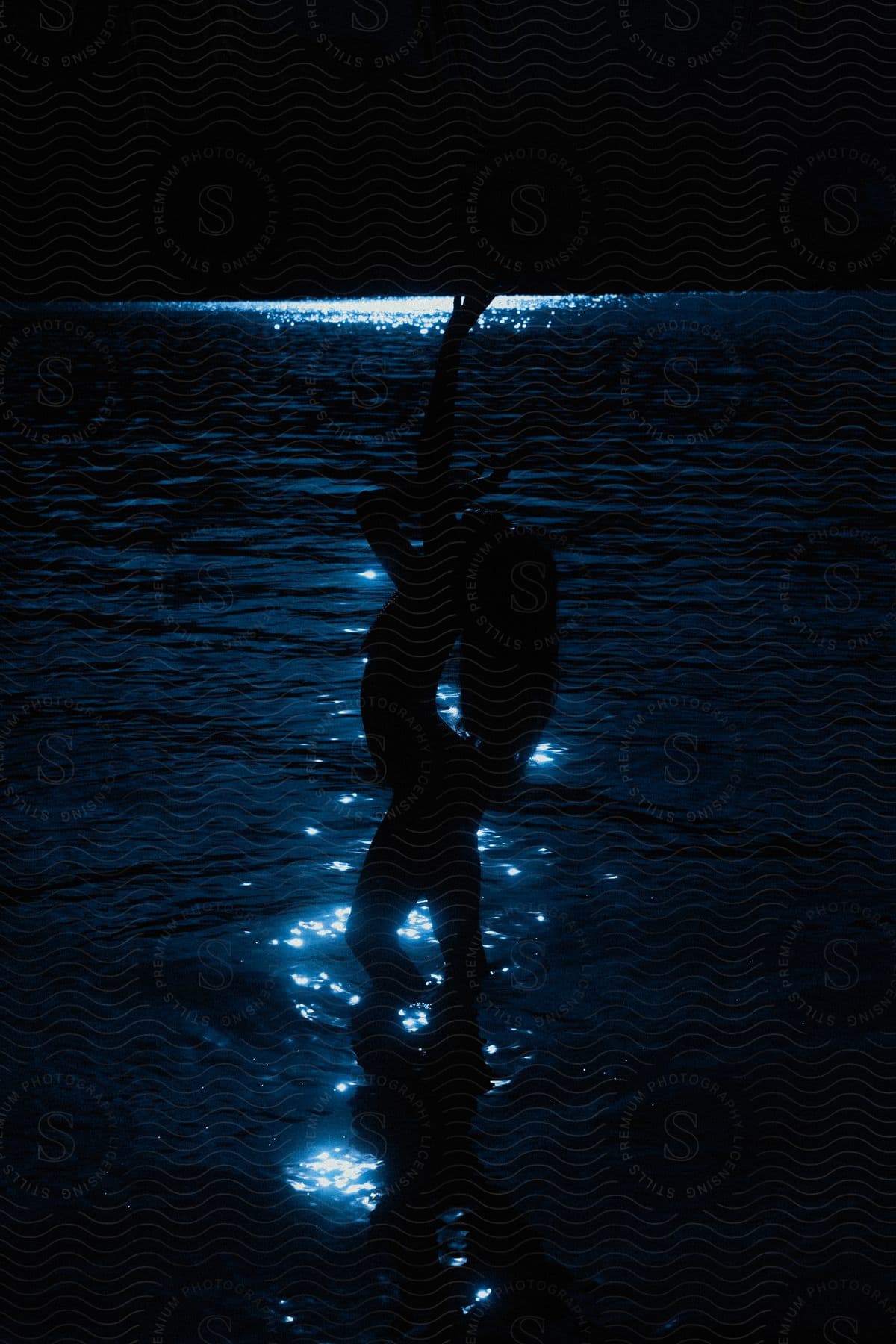 A woman posing in the water silhouetted against moonlight