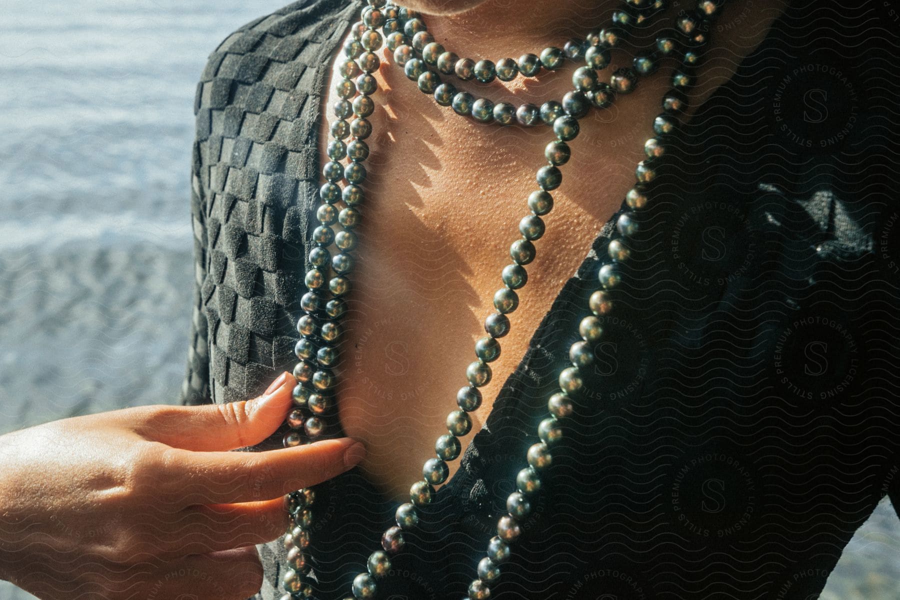 A polynesian woman stands alone on a black sand beach wearing body jewelry