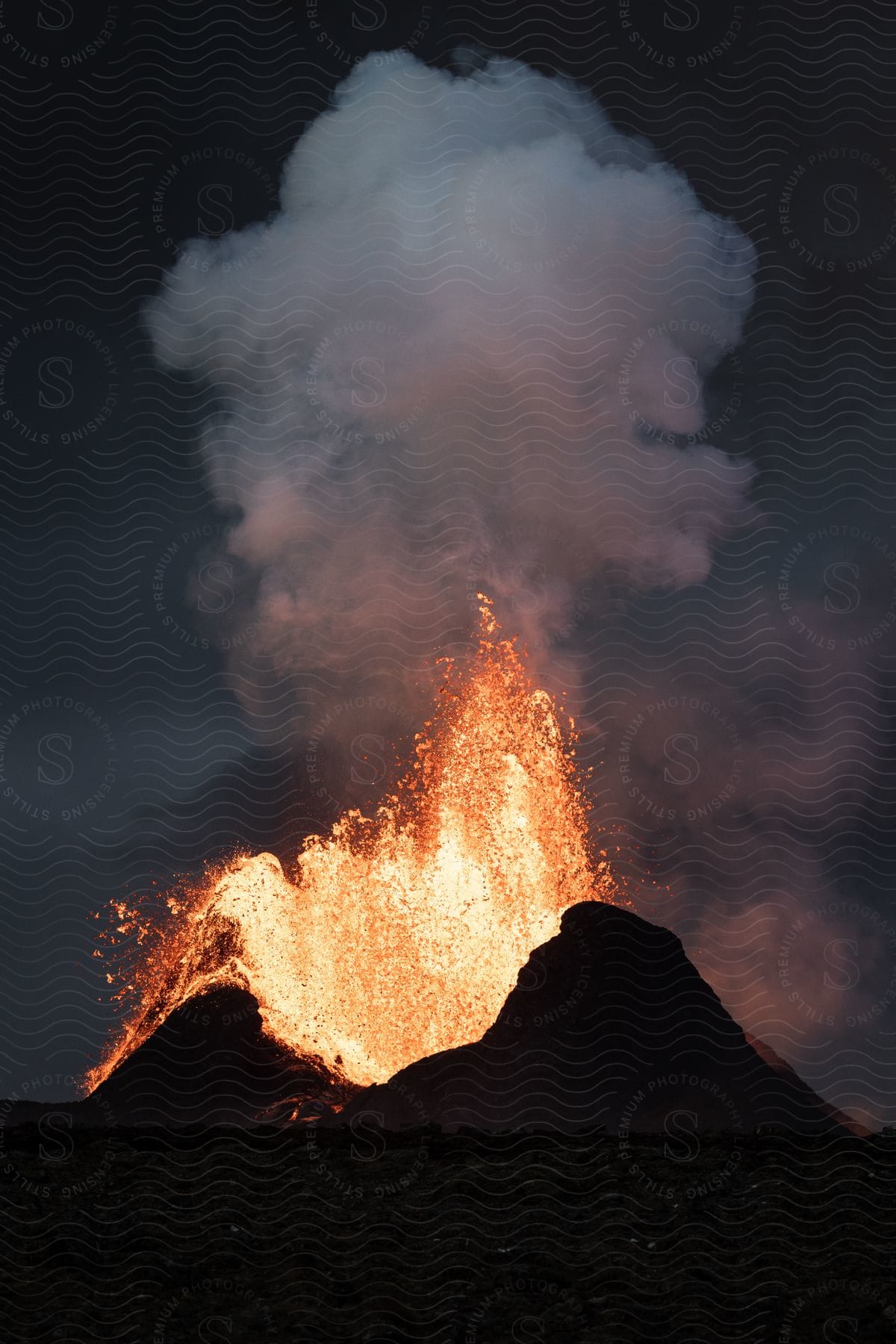 Erupting volcano emitting heavy smoke at night