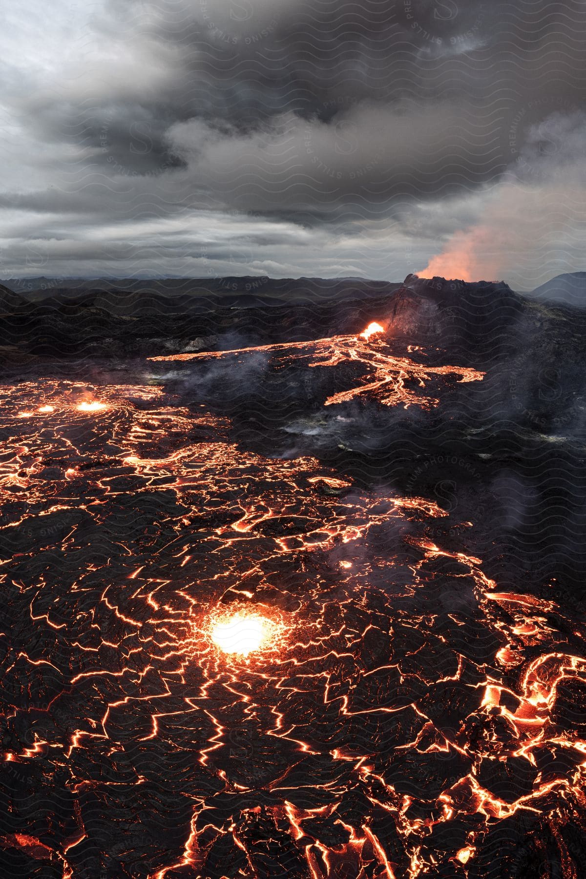 A volcano erupting and releasing lava down a mountain at night