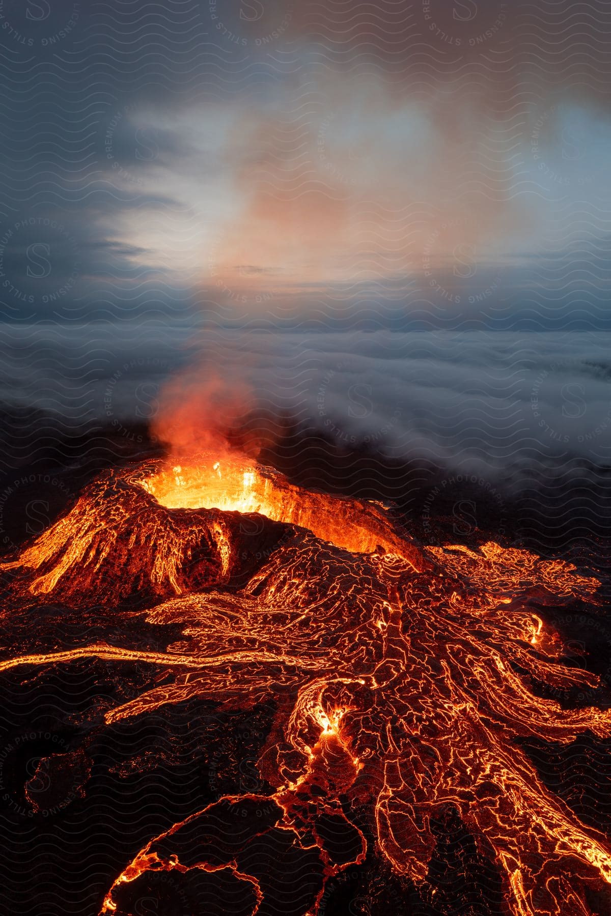 Stock photo of smoke rises from an erupting volcano as glowing hot lava flows