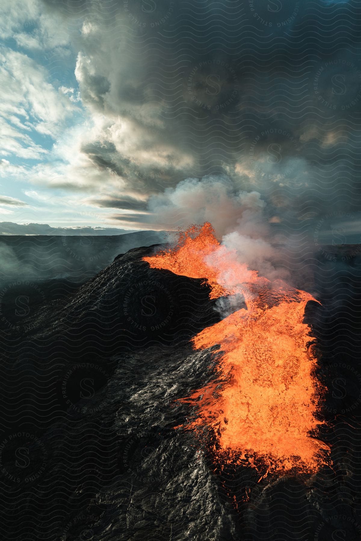 Stock photo of a volcano erupting and spewing hot lava down the mountain while smoking