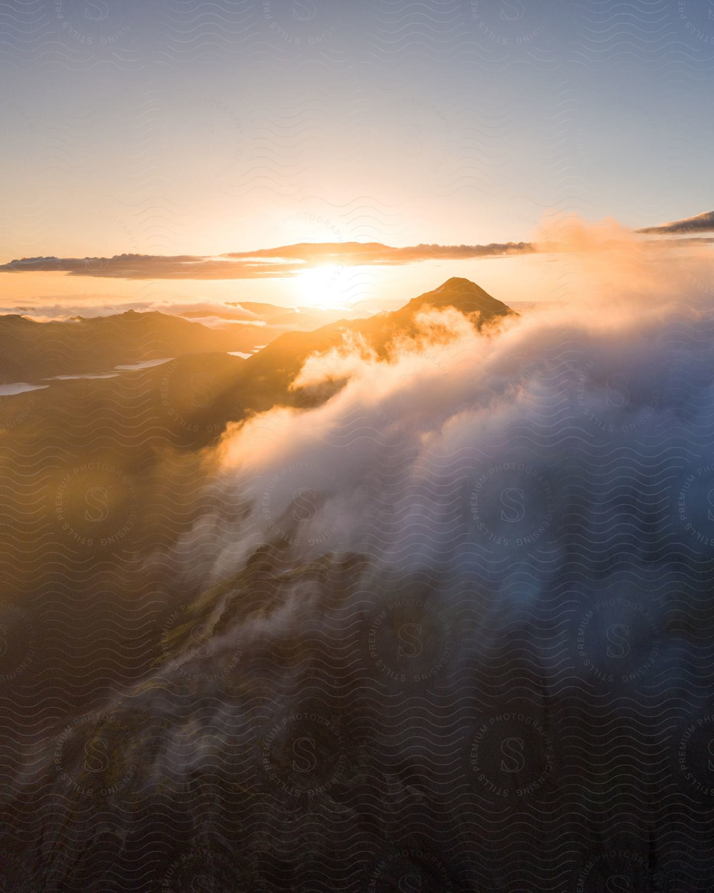 The sun shines over mountains in a cloudy sky