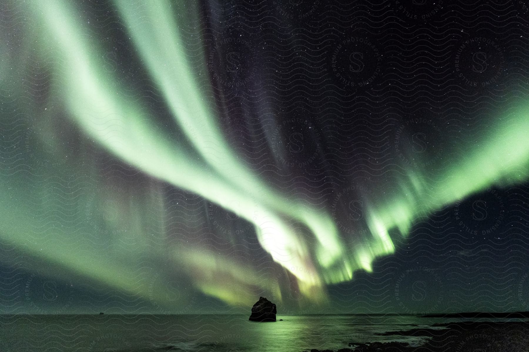 Wide landscape of the northern lights aurora borealis over the vast ocean at night