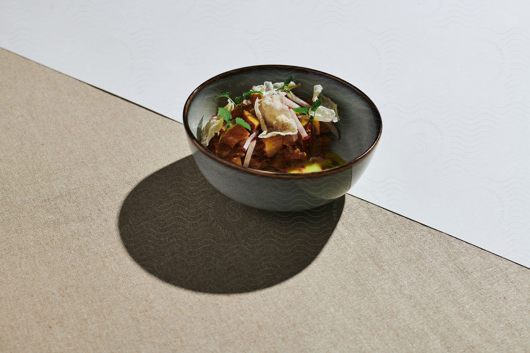 A bowl of stir fry with white noodles sitting outdoors on a surface