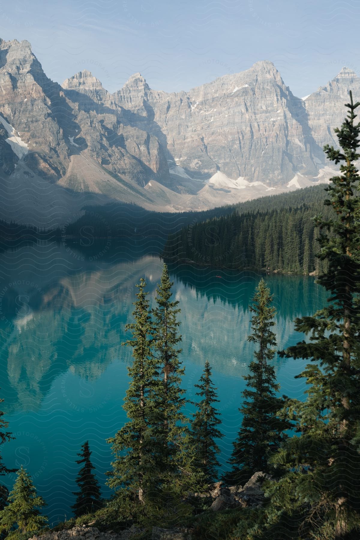 A mountain range is reflected on a lake surrounded by trees