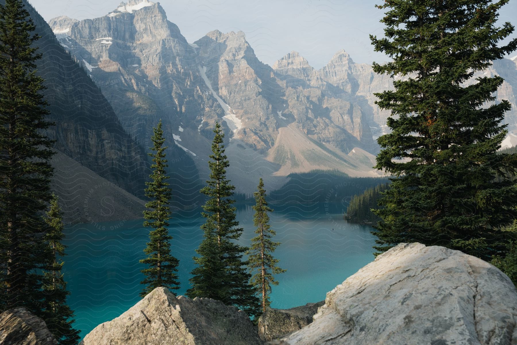 Green pine trees and rocks near lake and mountain on a sunny day moraine lake canadian rockies banff national park canada