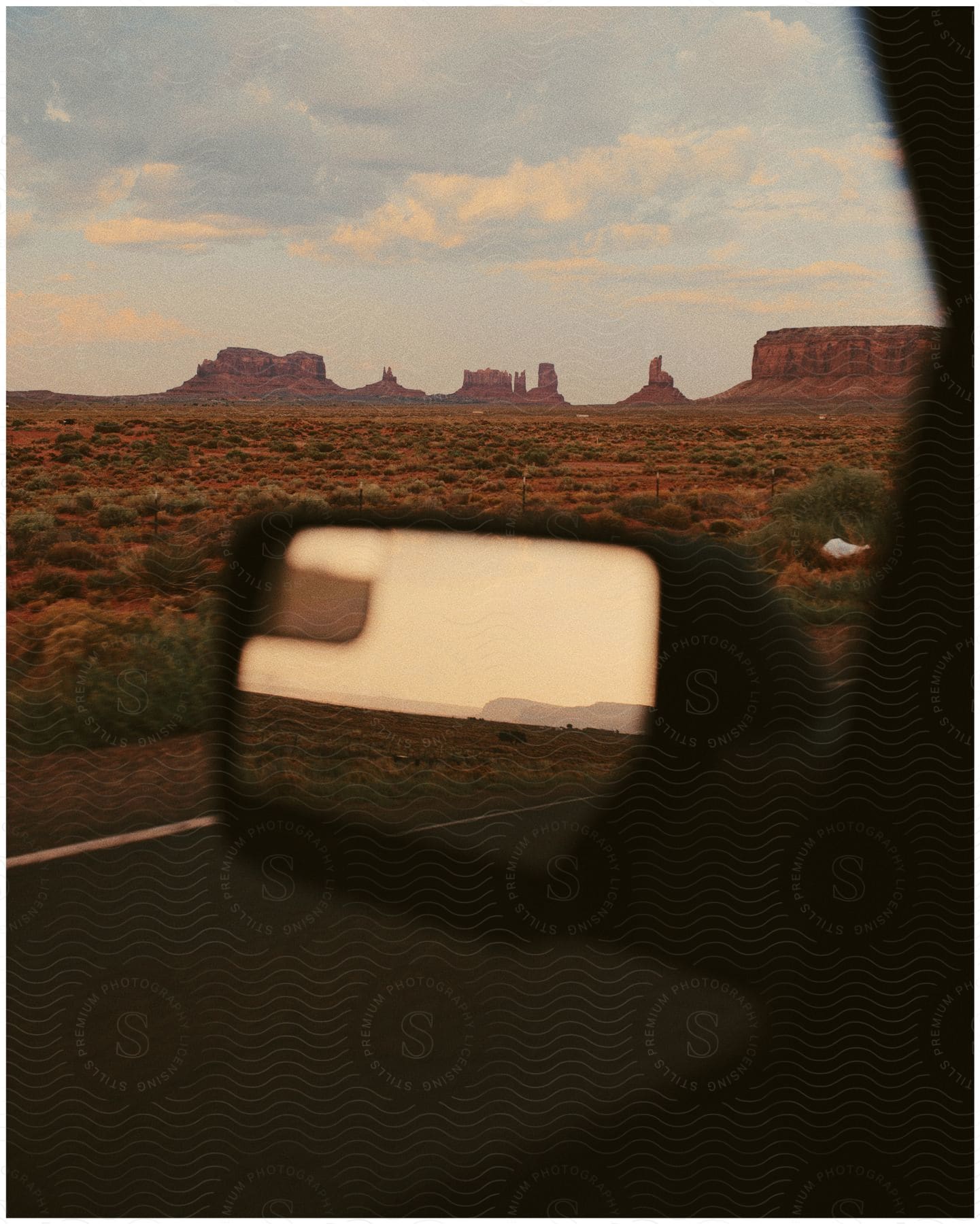 A landscape with mountains and a sky featuring a car mirror