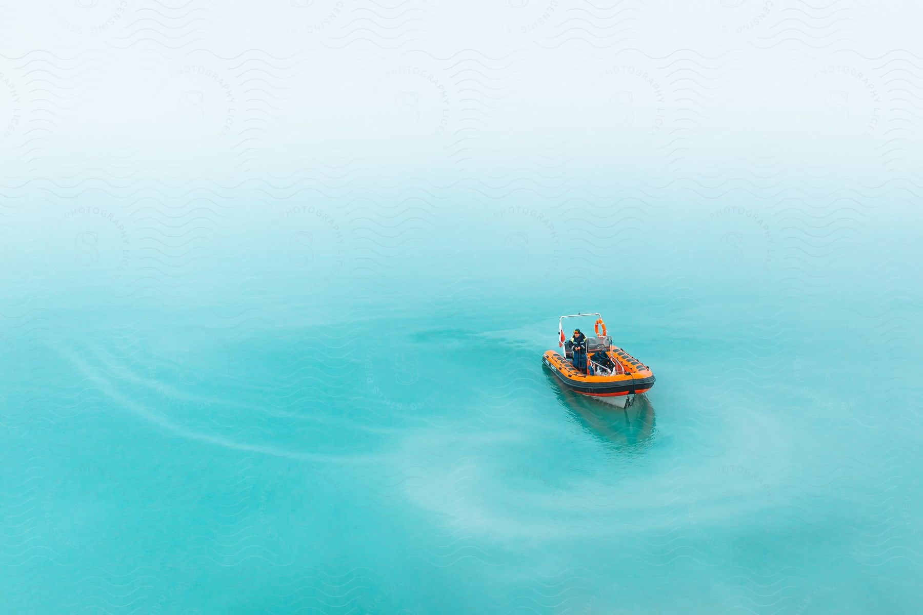 A person peacefully navigates a boat in the vast ocean with clear clouds above