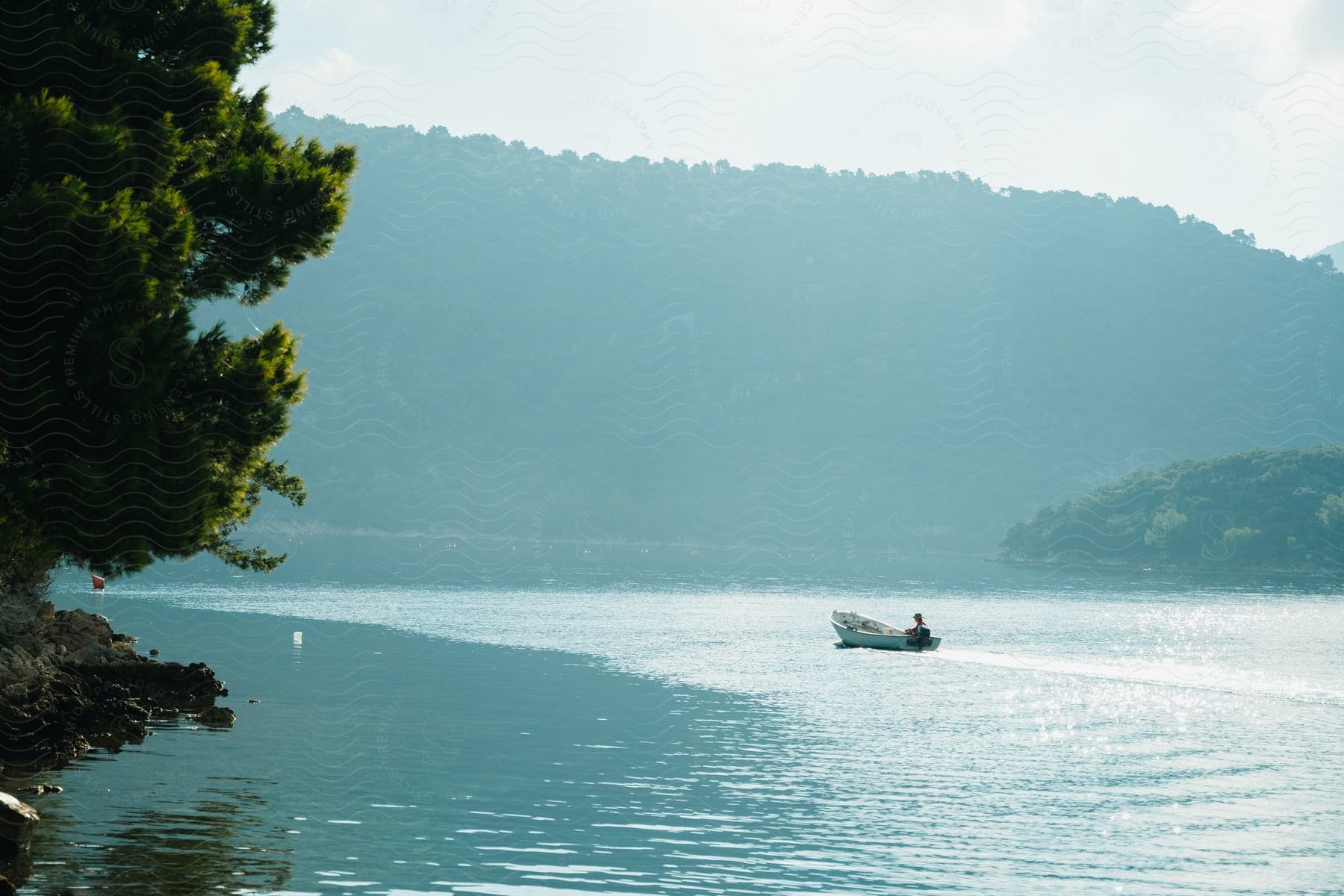 A small boat sails across a lake with a forested mountain in the background