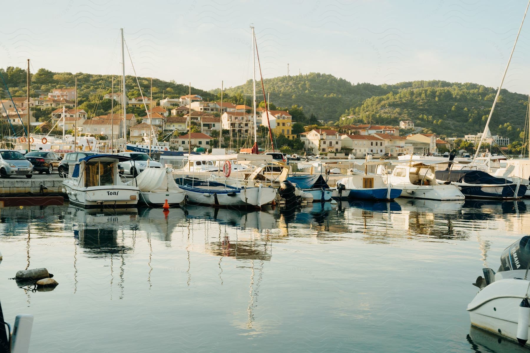 A row of boats huddled together at the dock in front of a hillside