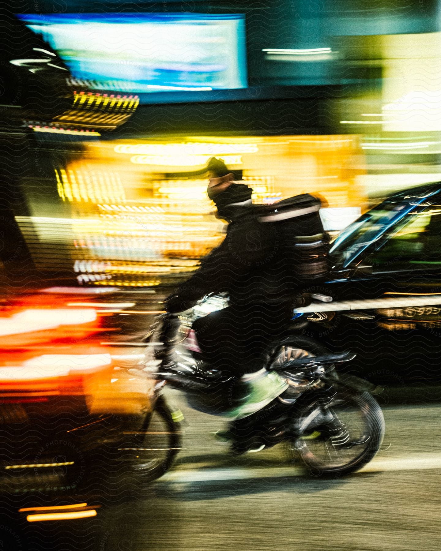 A man riding a bike with traffic in a blurry motion