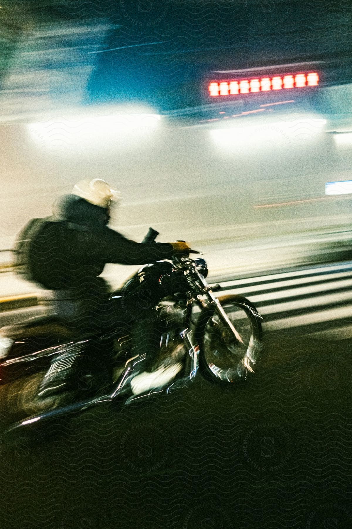 A person rides a motorcycle in blurred motion in front of a zebra crossing