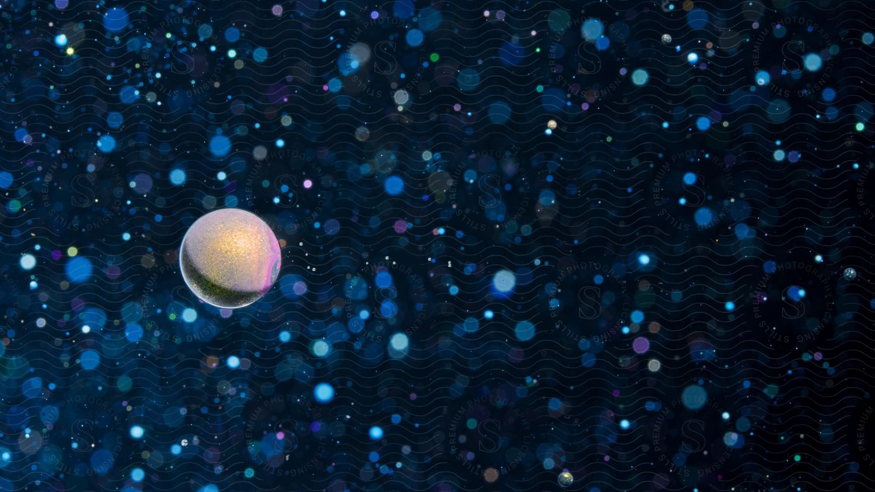 A sphere resembling a planet is illuminated by light while bokeh lights fill the surrounding darkness