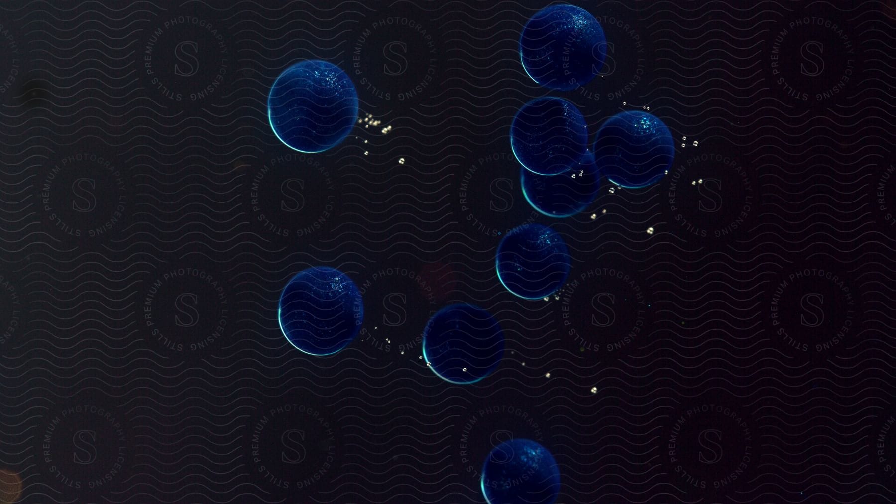 Several blue orbs speed through the black liquid leaving tiny bubbles in their wake