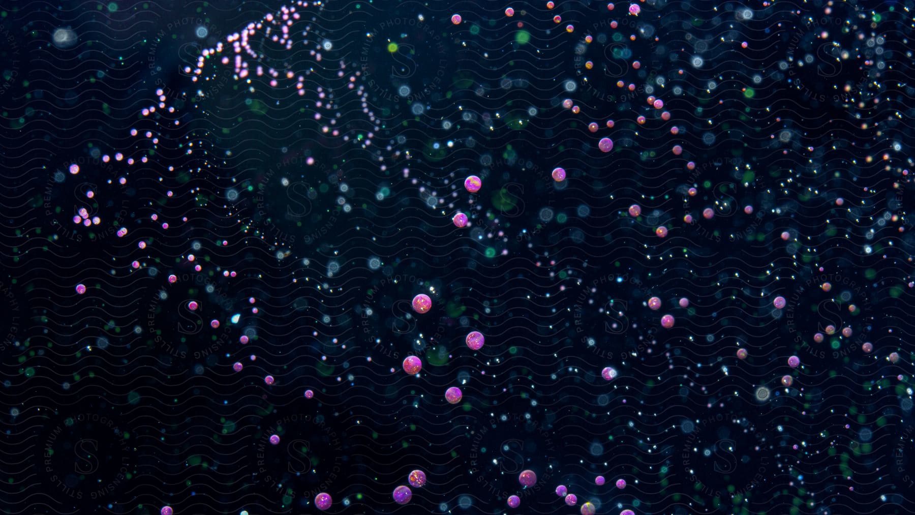 Radiant pink green and blue circles and dots dispersed across a dark background