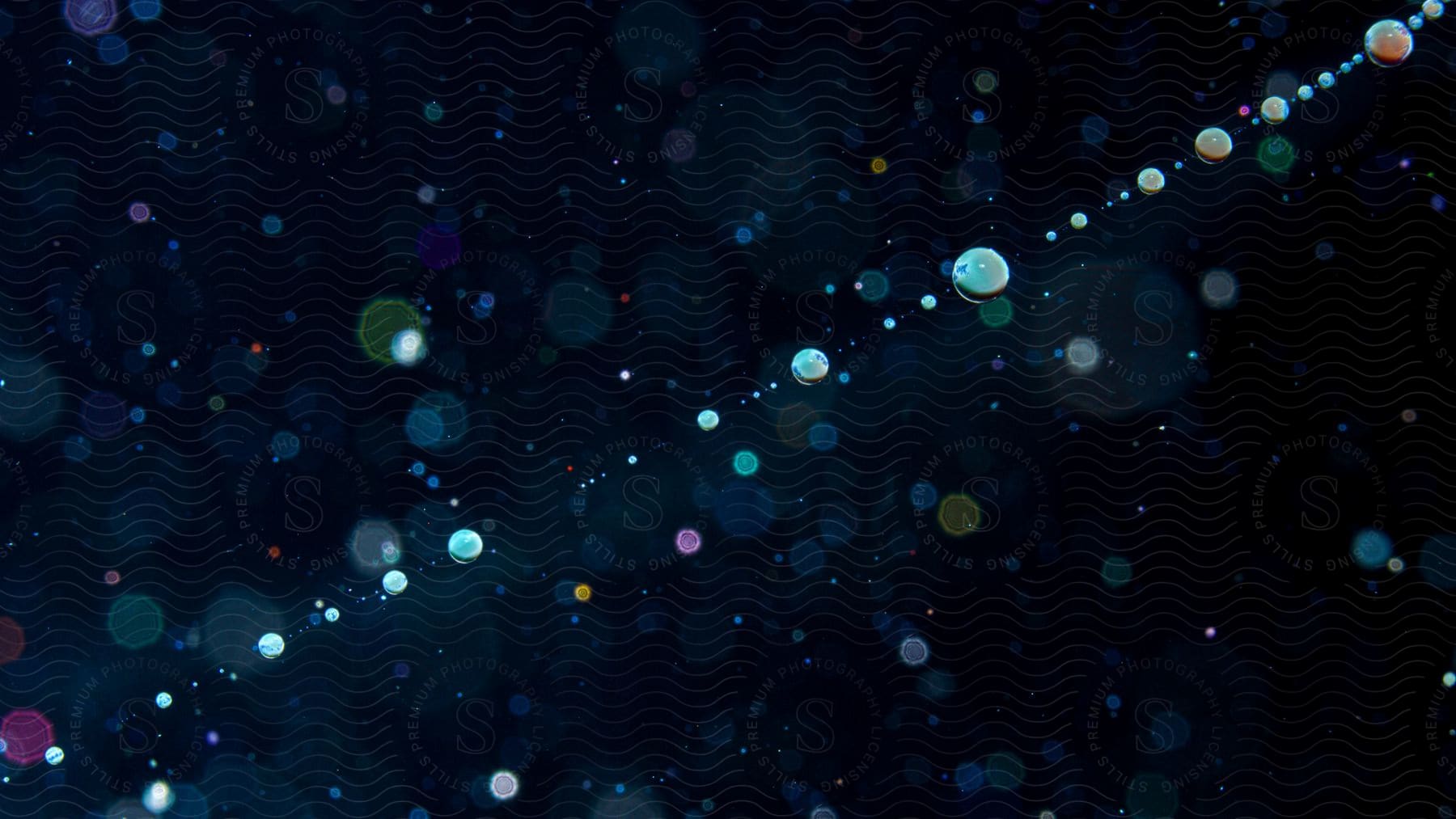 Dots and circles of different sizes and colors scattered over a dark background