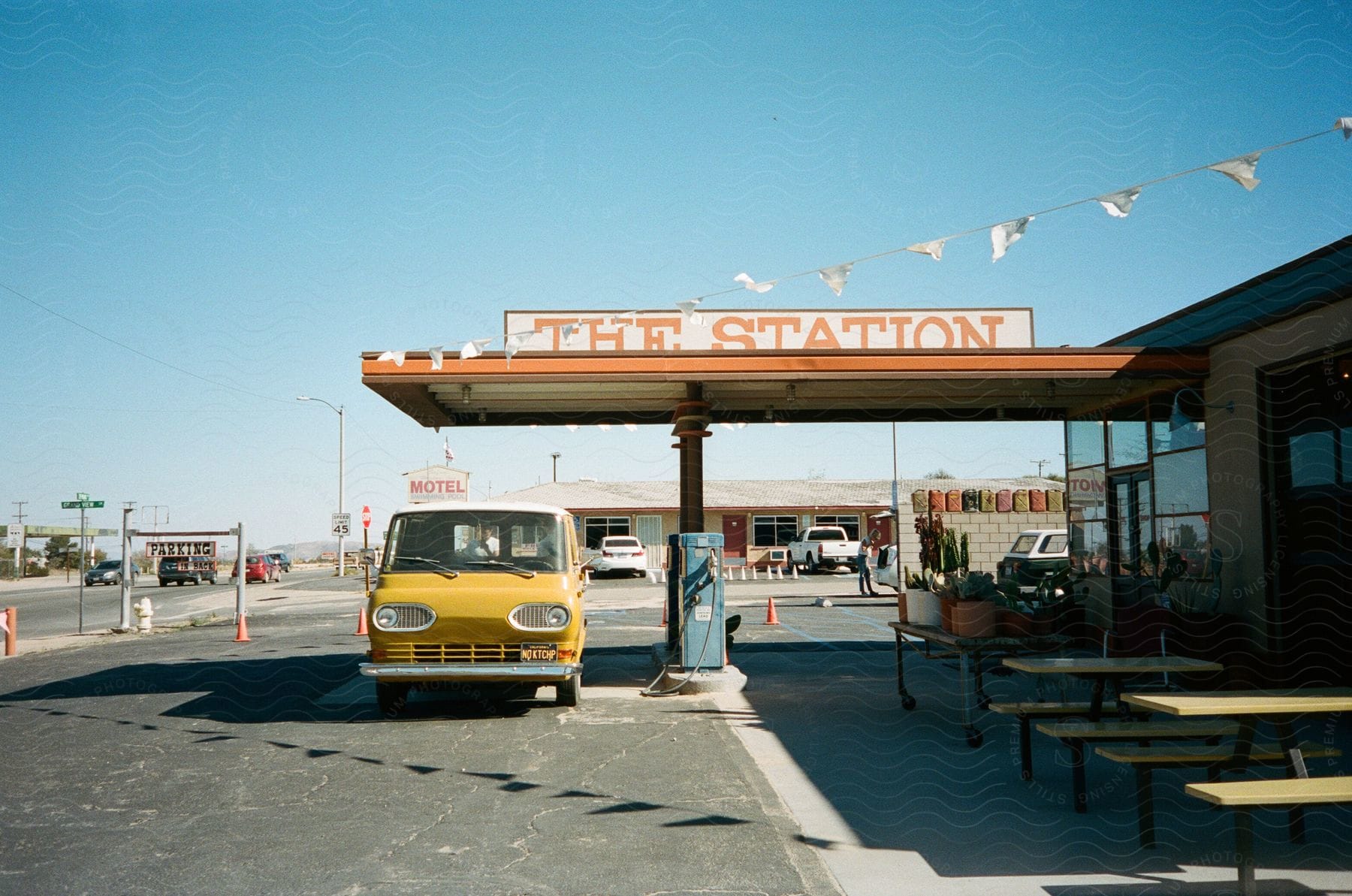 A yellow vintage van is parked outside of a gas station