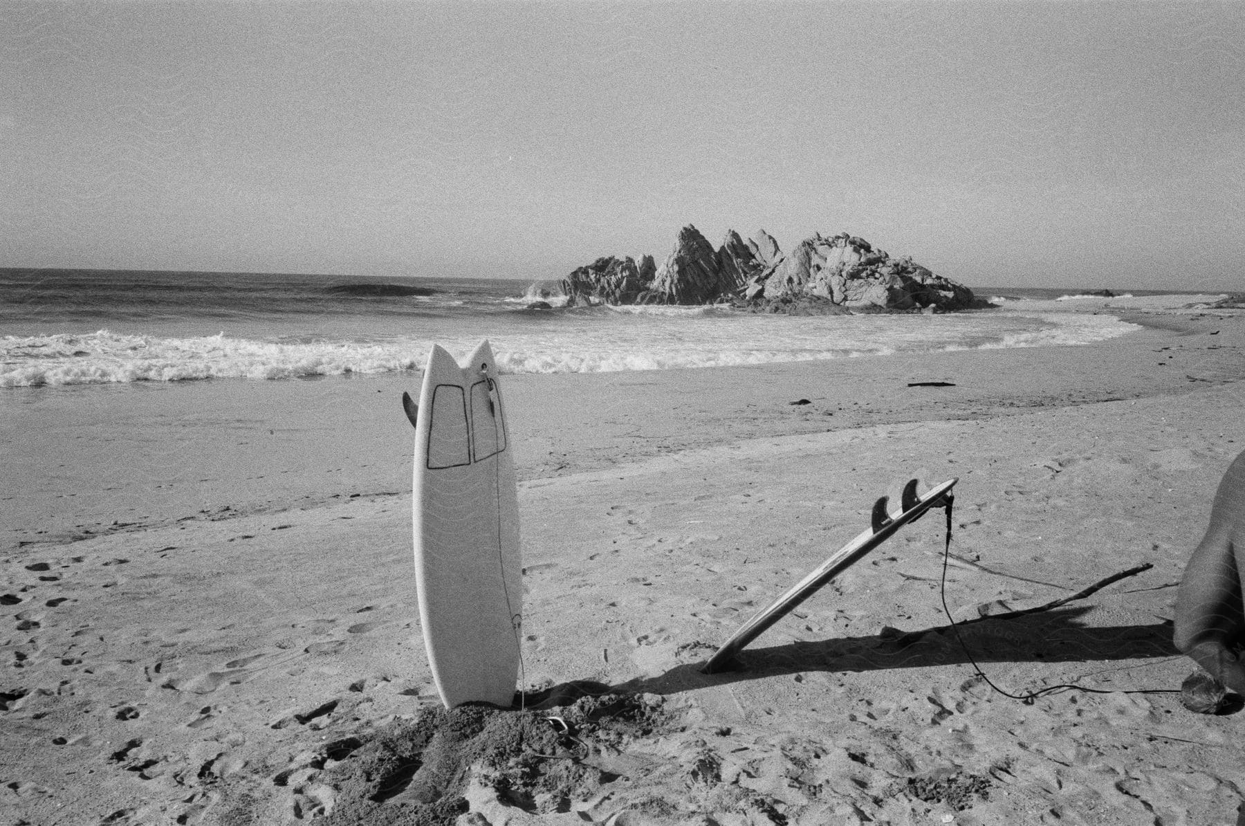 A surfboard is partially buried in the sand on a beach