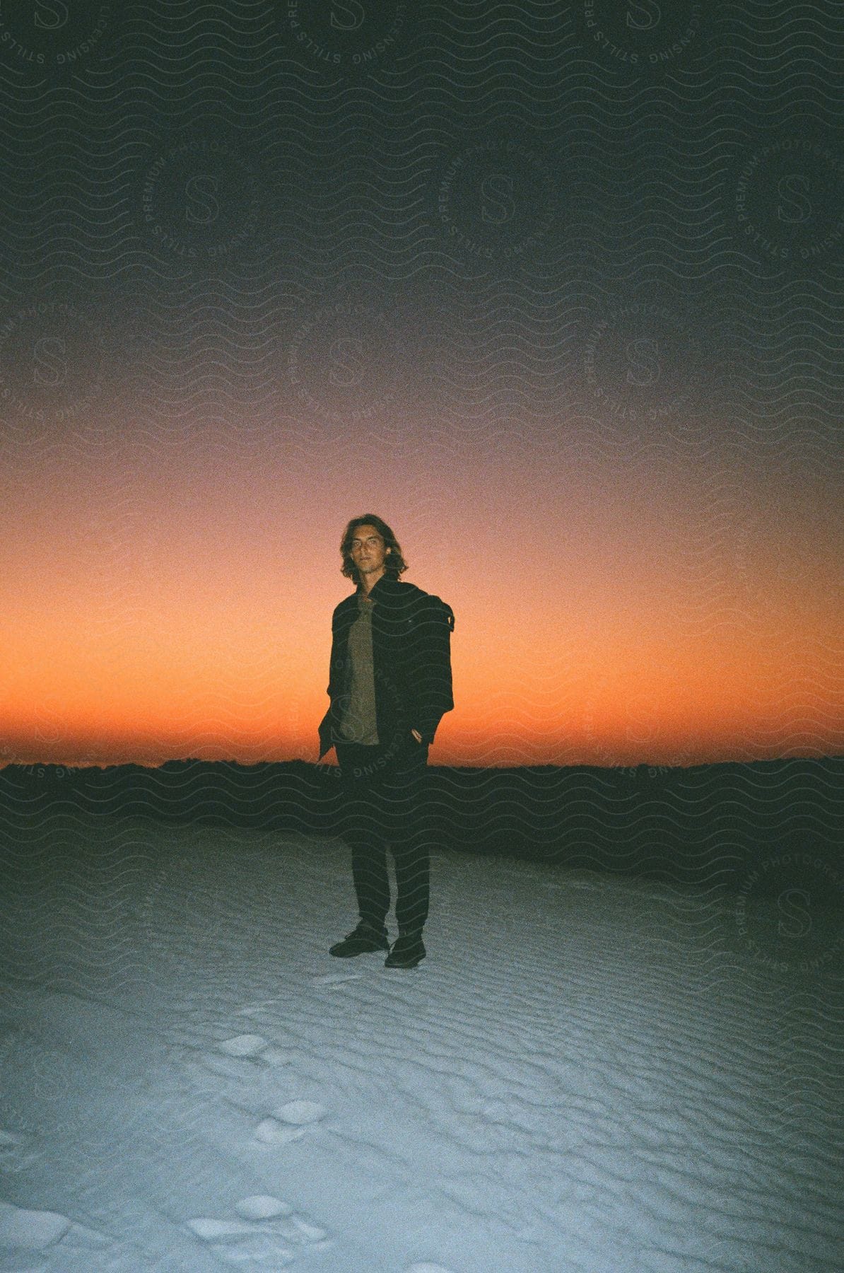 A man standing on the beach during sunset