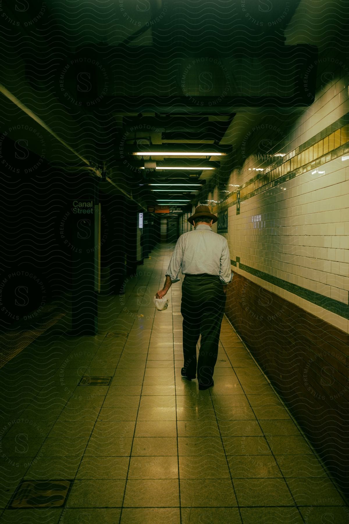 A man is walking through an empty hallway indoors at night time