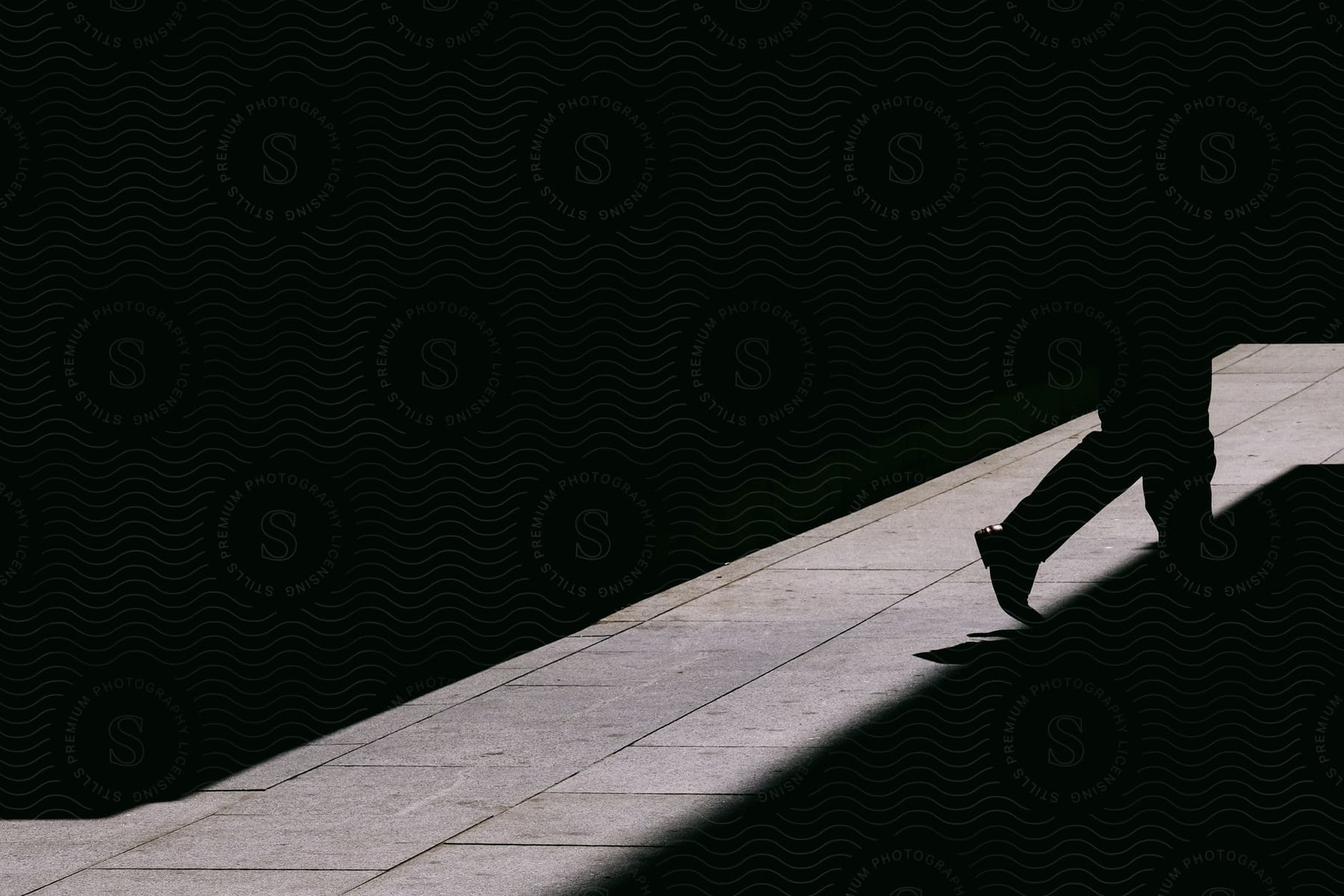 A man walking on a road surface in silhouette