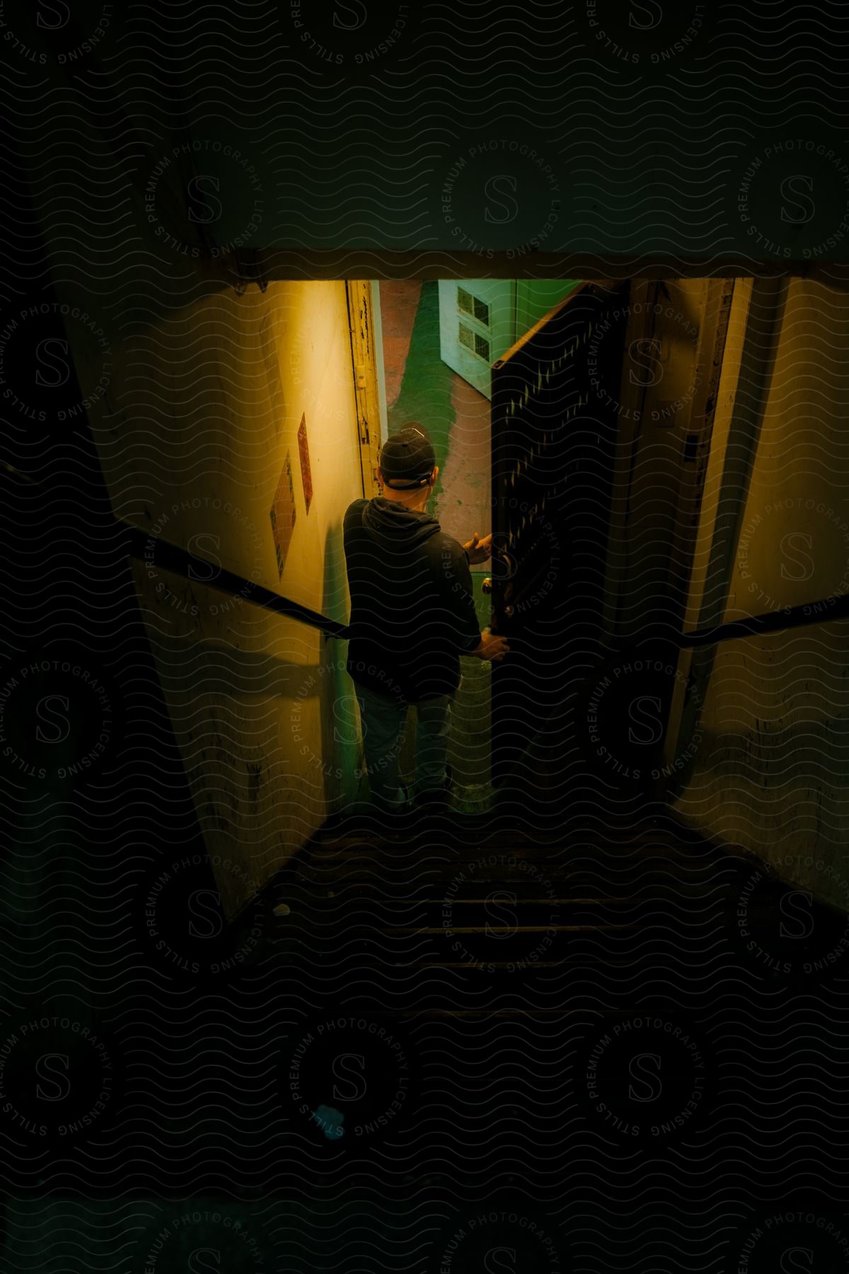 A man opens a door at the bottom of a dark staircase