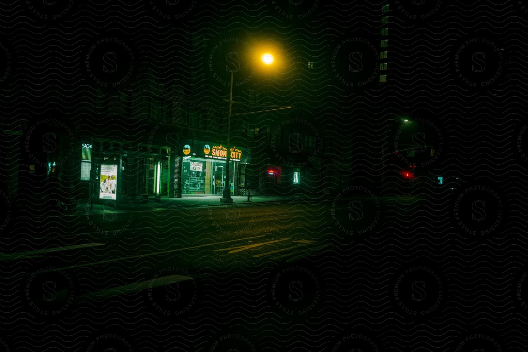 A dark urban city street at night with buildings and street lights