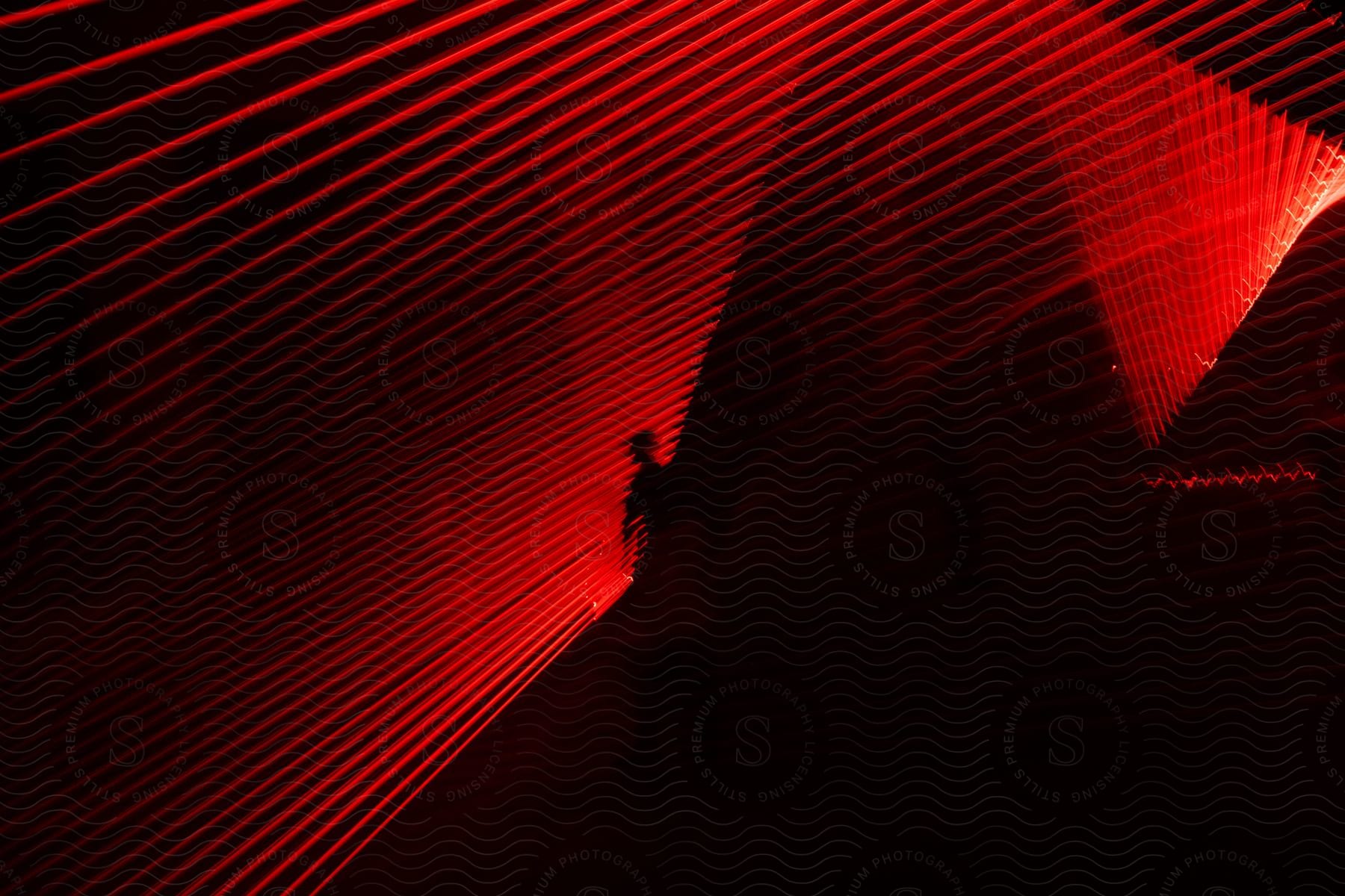A persons shadow is cast on a diagonal grid of red lights