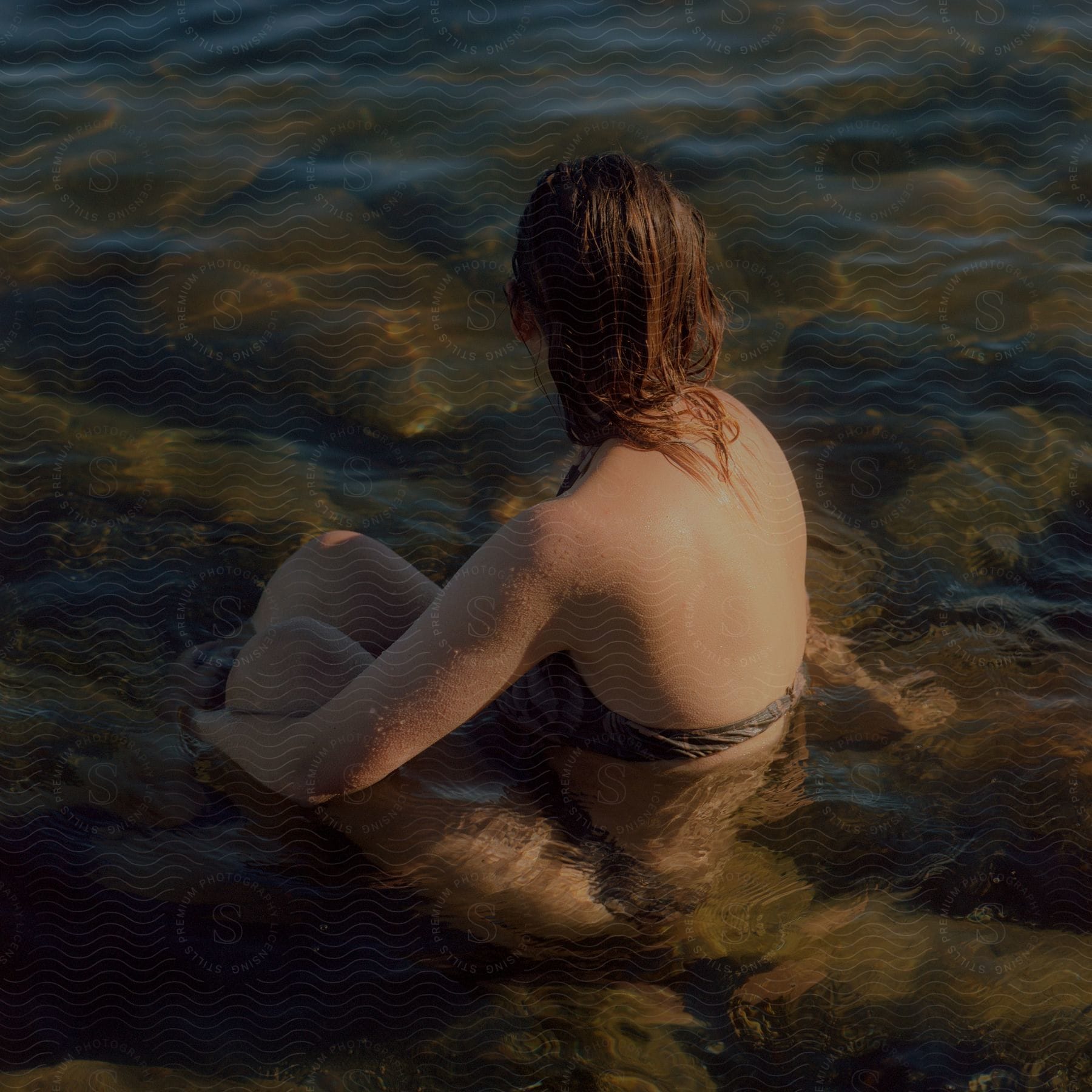 A woman sitting in water on a beach