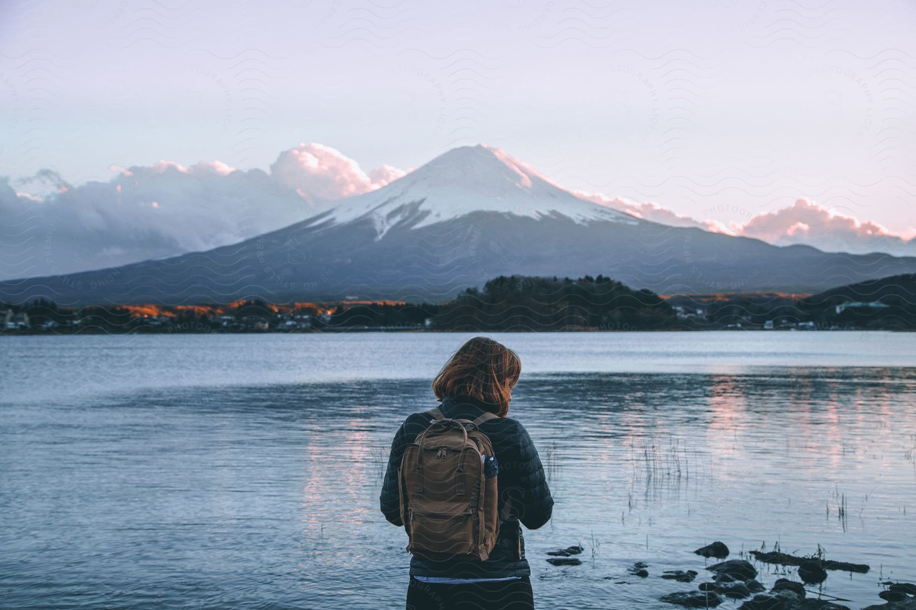 A woman standing near a beach with a mountain in front